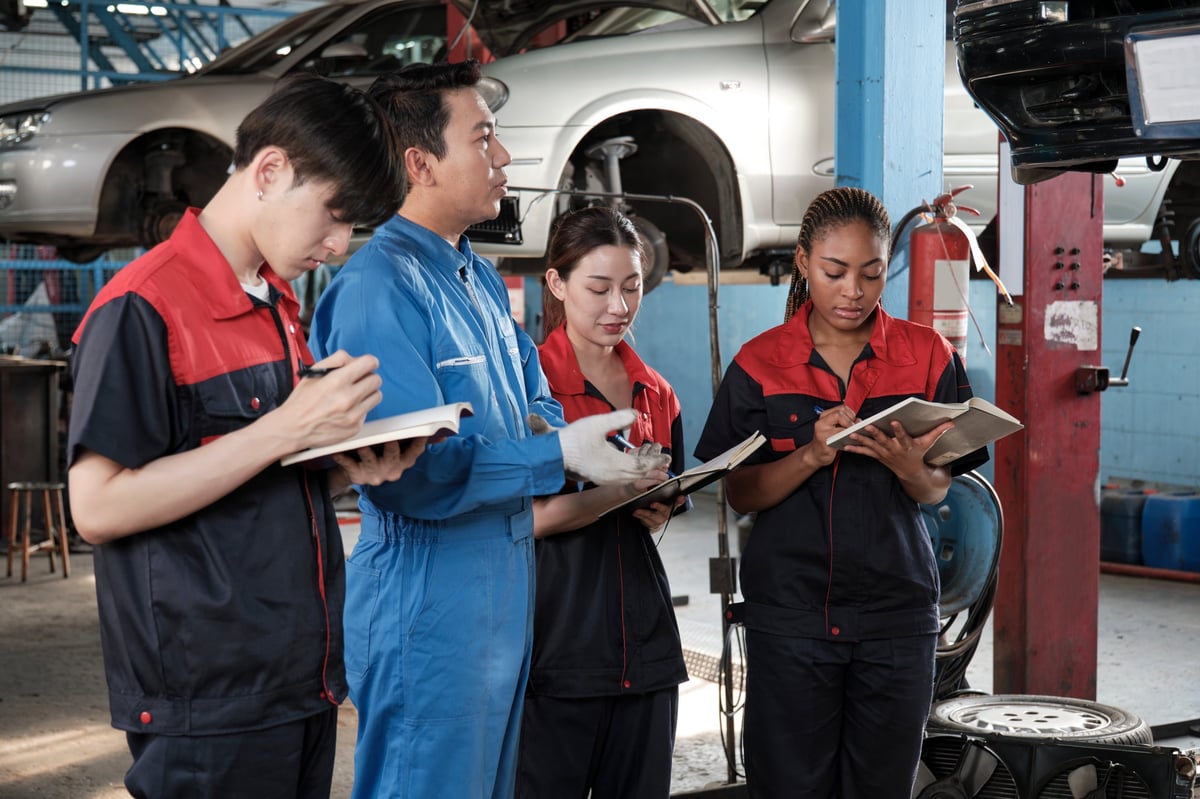 Specialist lecture. Male supervisor engineer describe automotive suspension fixing with mechanic worker staff teams for repair work at car service garage