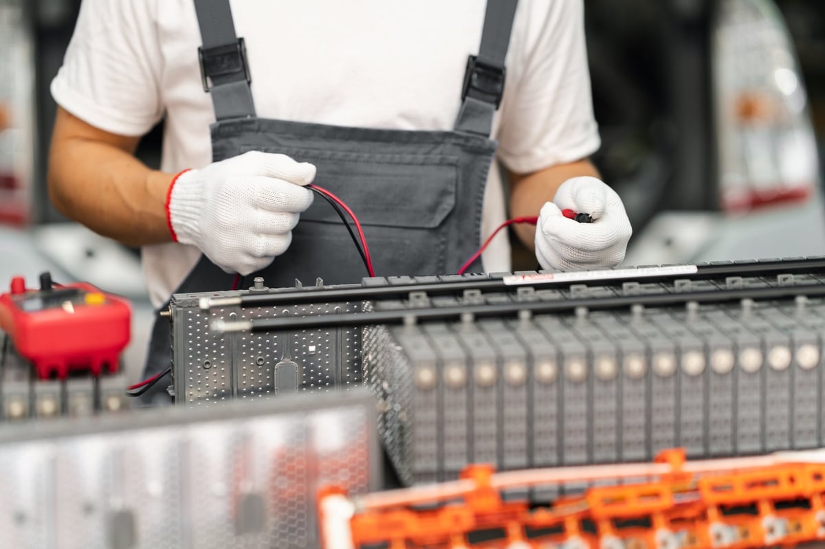 Serviceman repairs electric battery pack of hybrid car.