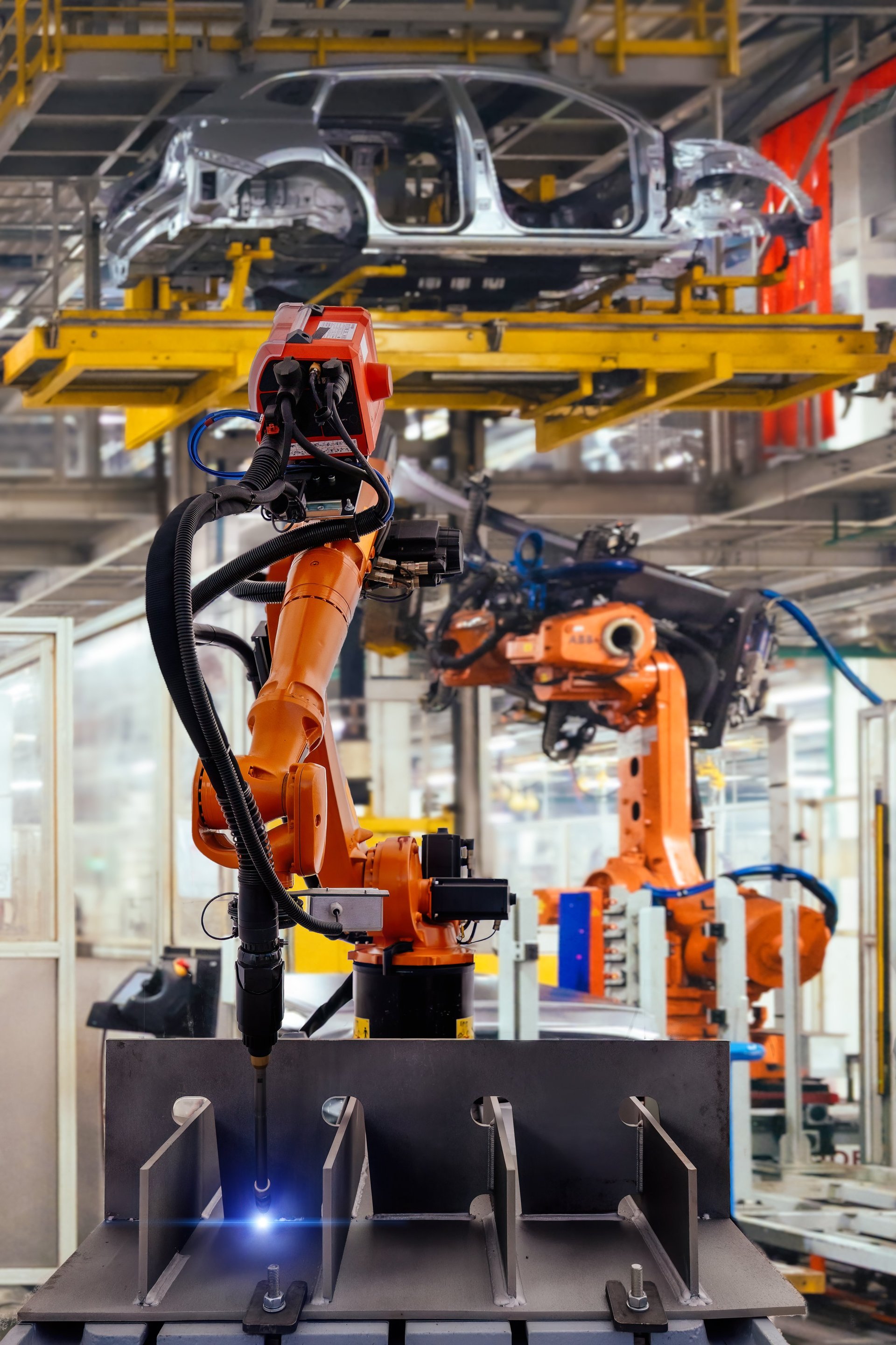 Industrial robot welding metal machine part in modern factory