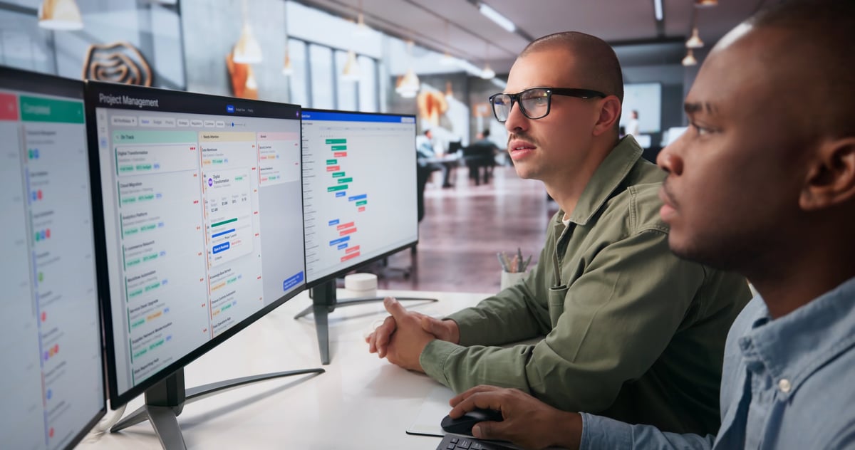 Two Project Managers Discuss Detailed Gantt Chart Schedules On Computer.